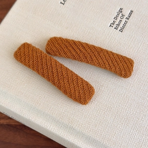 Detailed close-up of caramel knitted BB hair clips with textured diagonal weave pattern