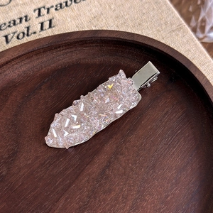 Macro d'une pince à cheveux en cristal champagne sur tissu vintage et plateau