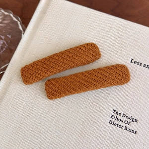 Macro shot of two orange-brown knitted hair clips with fine woven texture on a book