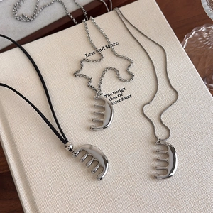 Gros plan détaillé de trois colliers pendentifs peigne avec chaînes cuir, croix et serpent