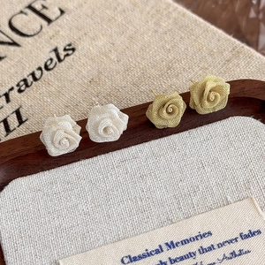 Detail of silver and gold mesh rose earrings featuring elegant woven metal texture