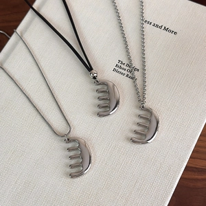 Vue détaillée de pendentifs peigne argentés avec chaîne serpent, cordon cuir et maillons