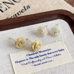 Stereoscopic mesh rose stud earrings set in gold and silver finish on vintage tray