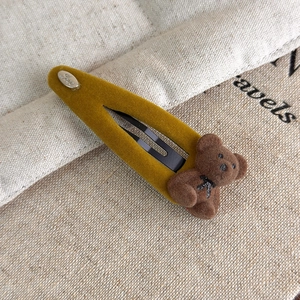 Détail de la barrette à ours floqué jaune gingembre avec un petit nœud noir élégant