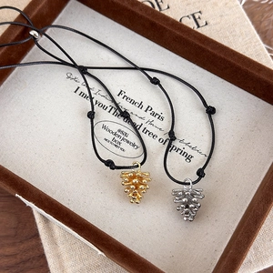 Detailed view of matte pinecone pendants in gold and silver on adjustable black cords