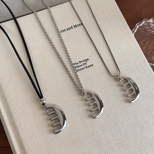 Lot de trois colliers à pendentif peigne en argent poli avec diverses chaînes sur un livre