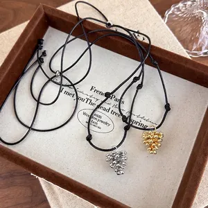 Adjustable black rope necklaces with gold and silver pinecone pendants in a gift box