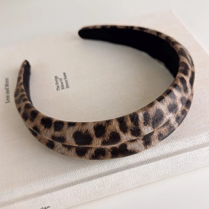 Close-up of wide leopard print headband with faux leather texture on white book