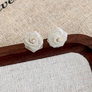 Close-up of 3D mesh rose earrings showing delicate white layers and handcrafted texture