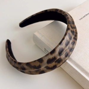 Close-up of leopard print headband with faux leather texture on a white book surface