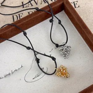 Macro detail of pine cone pendant necklaces with adjustable black cord in a wooden box