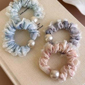 French style pearl lace scrunchies in soft pastel colors displayed on a textured book