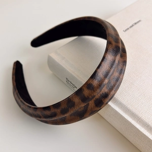 Close-up of leopard print faux leather headband with textured finish on a white book