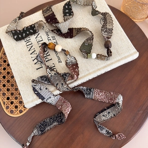 Détail du collier en tissu paisley vintage avec perles en bois et lin tressé
