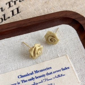 Detail of copper wire mesh rose earrings with matte gold finish and mesh texture