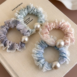 Detail of four colorful marble pattern scrunchies with white lace edges and large pearls