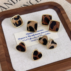 Gros plan de boucles d'oreilles léopard en forme de cœur et de carré avec bords dorés