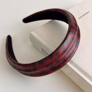 Detailed view of red leopard print faux leather headband with thick padded texture