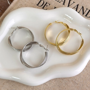 Multi-layer matte gold and silver twisted hoop earrings on a ceramic display tray