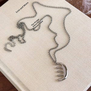 Détail du pendentif en métal en forme de peigne avec fermoir réglable sur livre