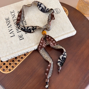Détail d'un collier en tissu imprimé paisley avec perle en bois et style rétro