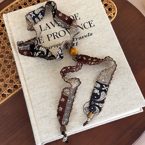 Détail d'un collier en tissu à fleurs bohème avec perle en bois et textures vintage