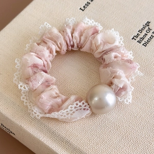 Detail of pink mesh scrunchie with white lace trim and a large elegant pearl ornament