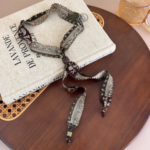 Détail du collier écharpe en tissu à motif paisley avec boucle en bois sur un livre ancien