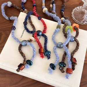 Handmade bohemian knit necklaces with colorful ceramic and wood beads on a book