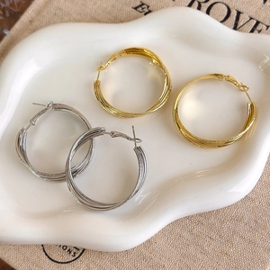 Close-up of interlocking multi-layer gold and silver hoop earrings with matte finish