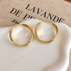 Close-up of golden triple-layered twisted hoop earrings with frosted matte texture finish
