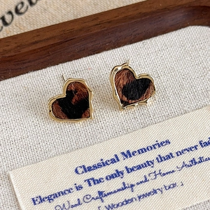 Gros plan de boucles d'oreilles cœur léopard avec bordure dorée sur un support texturé