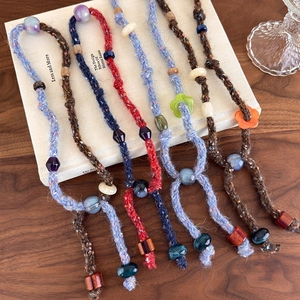 Detailed view of handmade knitted beaded necklaces in various color schemes and textures