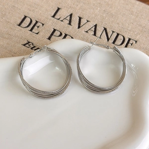 Detail of silver multilayered twisted hoop earrings with matte and polished texture