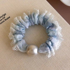 Detailed shot of light blue tie-dye hair scrunchie with white lace and large pearl