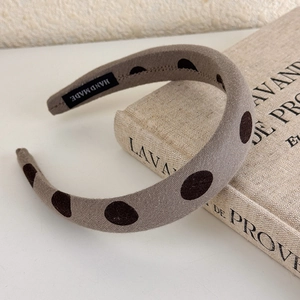 Detailed macro view of handmade brown polka dot fabric headband with soft inner label