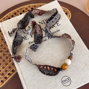 Détail d'un collier en tissu imprimé paisley bohème avec perles en bois sur un livre