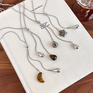 Tiger eye stone teardrop necklace with adjustable sliding chain on a book background