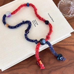 Detailed close-up of handmade knit beaded necklace with red and blue woven wool texture