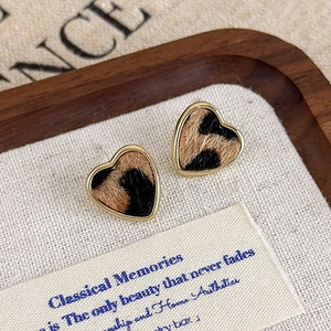 Vue détaillée de boucles d'oreilles cœur léopard avec bordure dorée et texture floquée