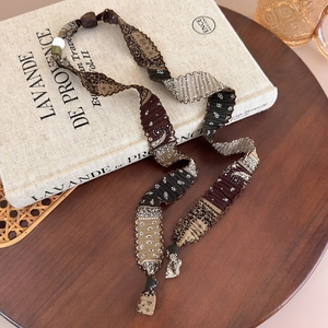 Gros plan d'un collier en tissu à motif paisley vintage avec perles sur un livre ancien