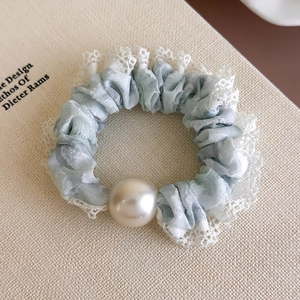 Close-up of light blue lace scrunchie with elegant pearl accent and delicate frills