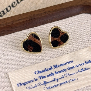 Gros plan de boucles d'oreilles cœur léopard avec bordure dorée sur support en lin