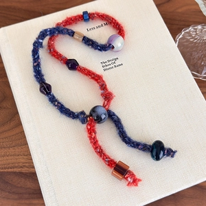 Detail of vintage hand-woven sweater chain with colorful beads on minimalist book