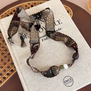 Détail du collier en tissu paisley avec texture plissée et perles décoratives terre