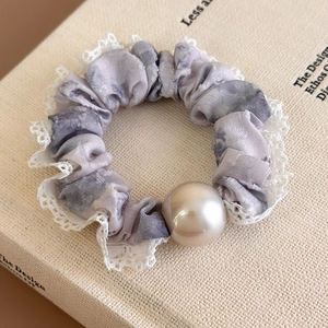 Close-up of floral scrunchie with white lace trim and a large pearl on book
