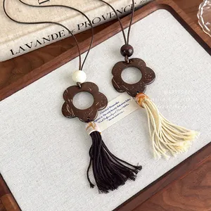 Vintage wooden coconut shell flower pendant necklace with long tassels on a woven pad