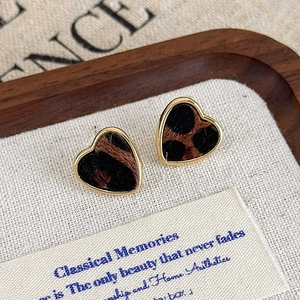 Vue macro des boucles d'oreilles cœur léopard avec texture crin de cheval et bords dorés