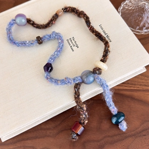 Detail of vintage hand-knitted drawstring necklace with colorful beads on a book