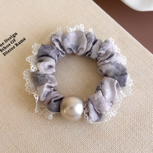 Detail of lavender tie-dye scrunchie with white lace trim and cream pearl accent